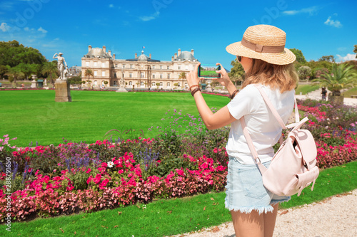 Young asian looking blogger taking pictures on smartphone for social networks of the urban landscape in the Luxembourg garden in Paris. Millennial Travel and lifestyle concept photo