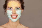 Portrait of beautiful woman with colorful cream mask on her face.