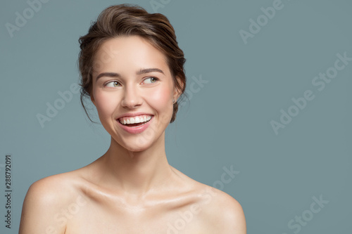 Portrait of smiling beautiful woman. Perfect skin. Blue background.