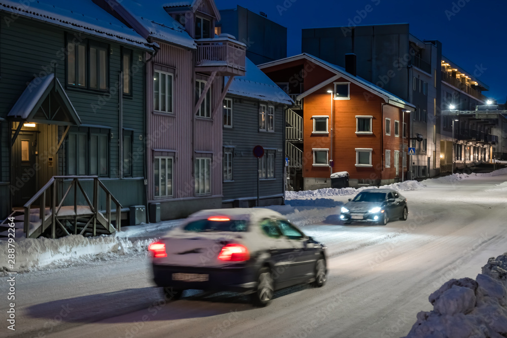 Cars driving slowly on snowy streets of Tromso
