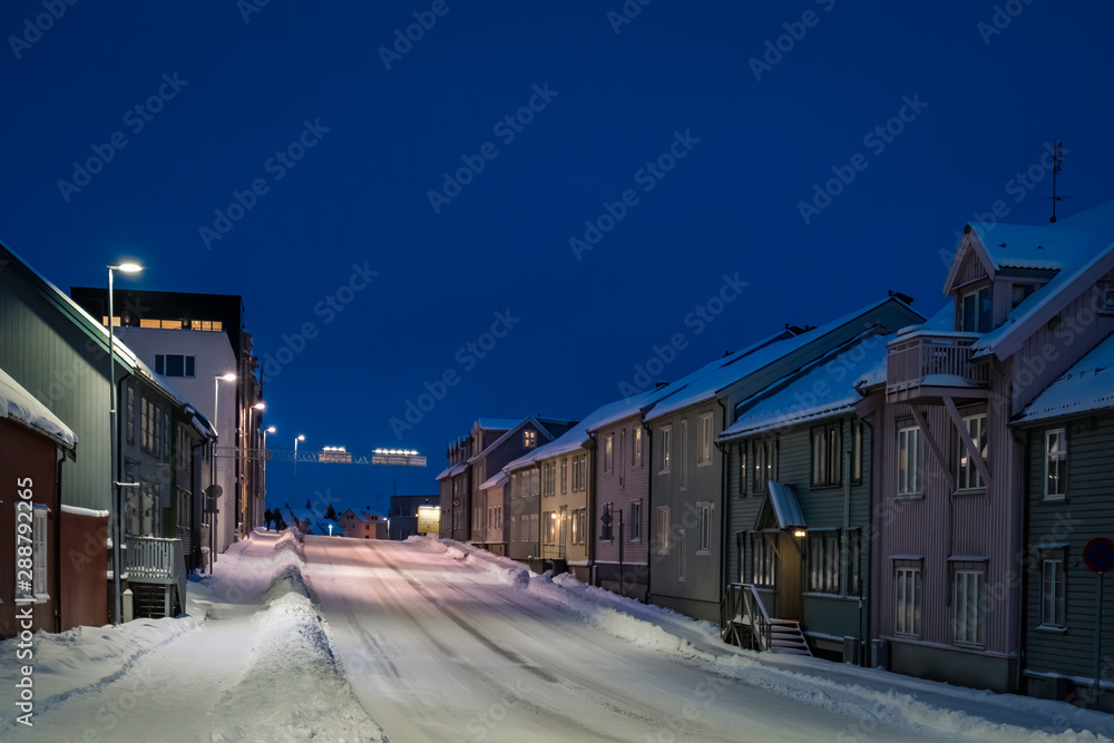 Empty snowy residential street in Tromso at dusk