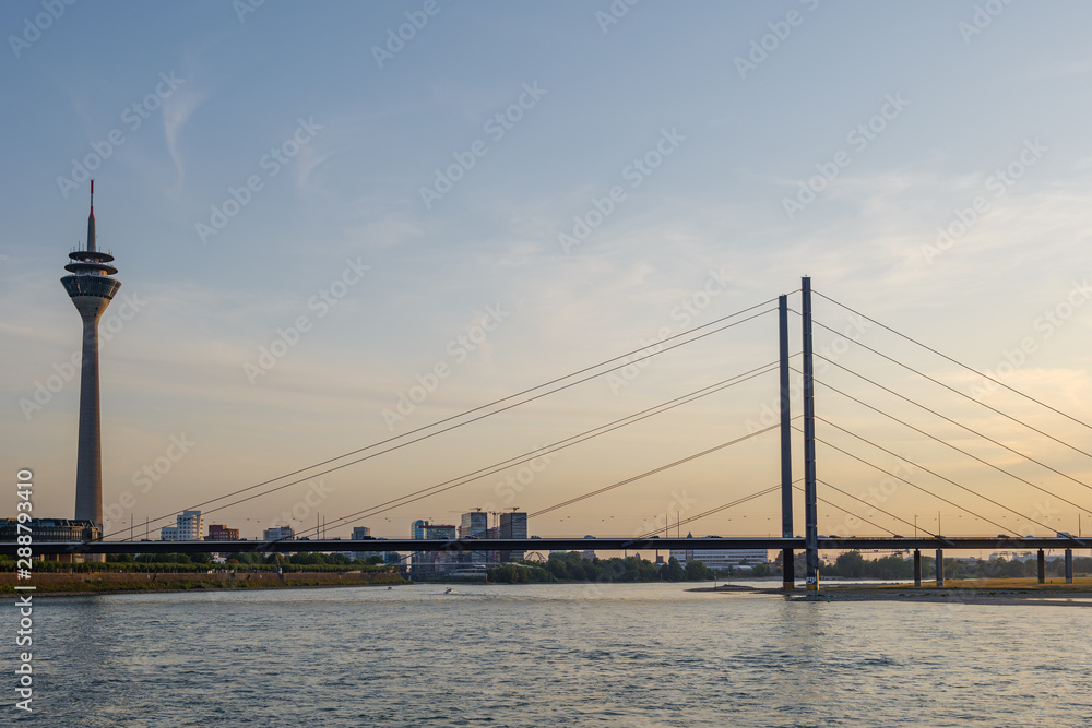 Outdoor scenery of Düsseldorf City skyline, downtown, tower bridge, riverside and Rhine River, and beautiful background of golden gradient sunset sky. 