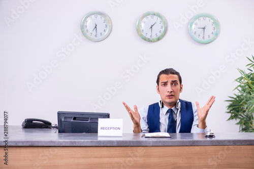 Young man receptionist at the hotel counter