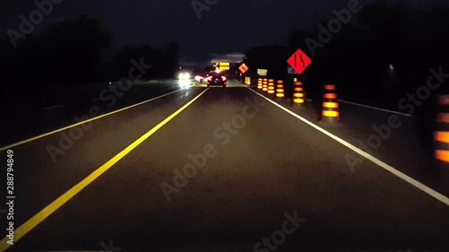 Driving Lane Ends Rural Road With Construction Marker Signs at Night.  Driver Point of View POV Orange Caution Road Signs While Driving Countryside Street in the Evening.