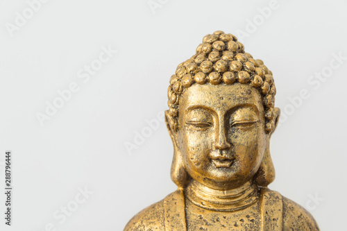 Generic golden statue of Buddha on white wall background. Interior decoration accessories abstract concept of balance zen meditation harmony. Inspirational poster with copy space