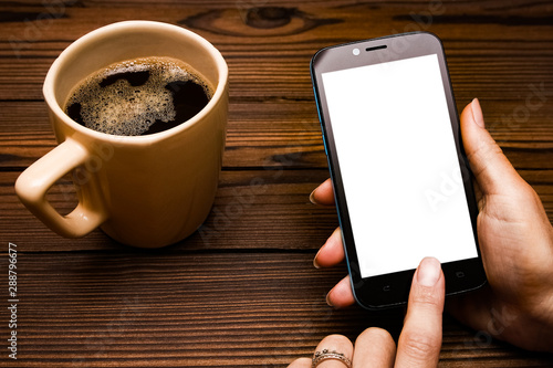 Female hands holding cup of coffee on wooden background