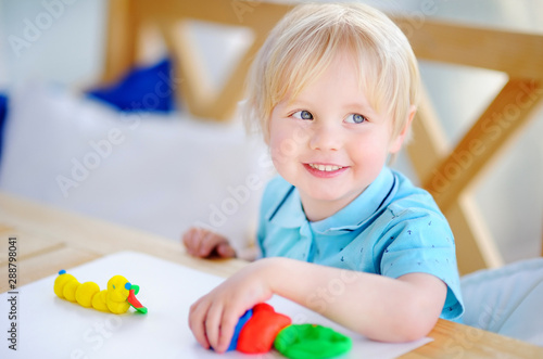 Creative boy playing with colorful modeling clay at kindergarten