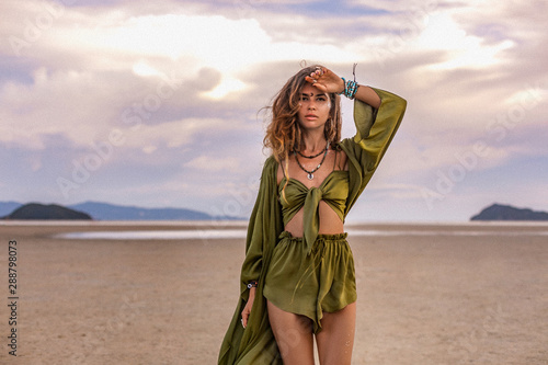 Obraz na płótnie beautiful young woman in stylish costume on the beach at sunset