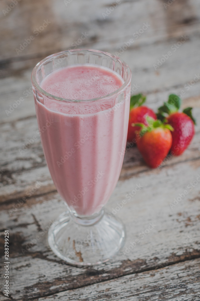 Batido de fresa con fondo de madera. A un lado fresas. Batido de fresa con fondo de madera. A un lado fresas.