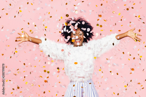 Happy young woman celebrating with arms out and lots of falling confetti photo