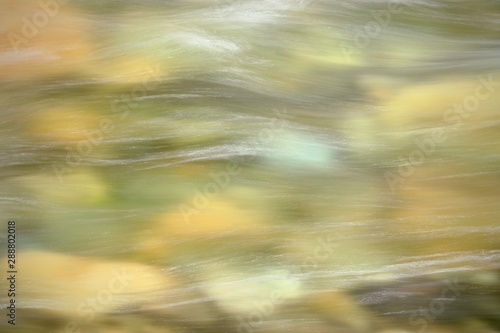flowing, rushing water rendered with a slow shutter speed blurs the water and the stones of a Sierra Nevada mountain stream in California