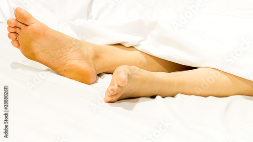 Closeup two feet on the bed a white background with sleeping at home relaxing in holidays.
