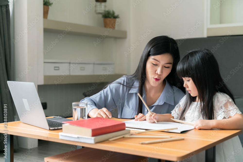 Beautiful mom using a laptop teaching homework with kids at home Beautiful mom using a laptop teaching homework with kids at home