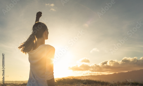 Young female outdoors with fist in the air feeling strong and confident. Victory and success concept.  photo