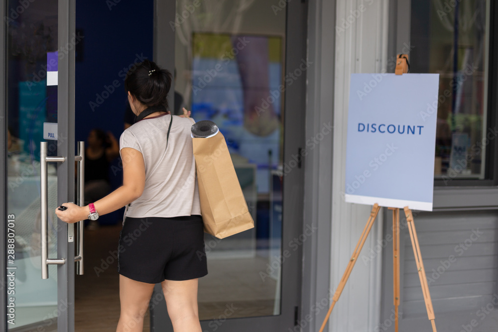 Unidentefied woman with paper shopping bags entering the shop. Unidentefied woman with paper shopping bags entering the shop.