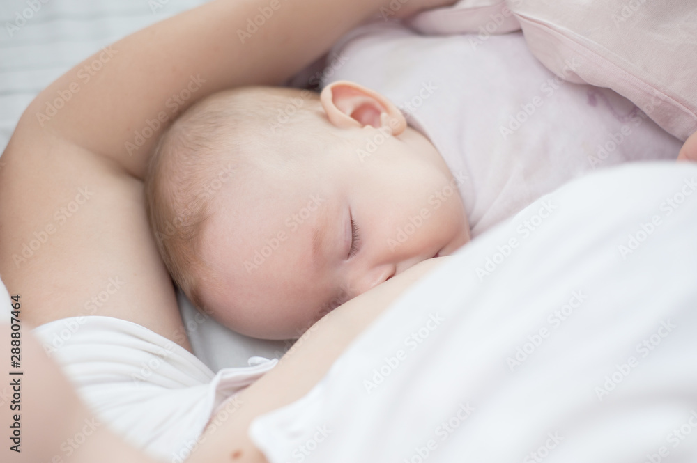 Mother holding newborn baby in an embrace and breastfeeding. Mother is breastfeeding her baby. Newborn breastfeed. Happy motherhood. Healthy eating. Happy motherhood. Caucasian child Mother holding newborn baby in an embrace and breastfeeding. Mother is breastfeeding her baby. Newborn breastfeed. Happy motherhood. Healthy eating. Happy motherhood. Caucasian child