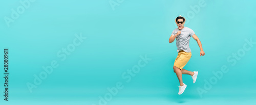 Amazed handsome Asian tourist man in summer outfit jumping