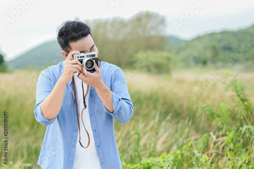 Asian photographer with vintage camera taking pictures in nature, lifestyle concept.