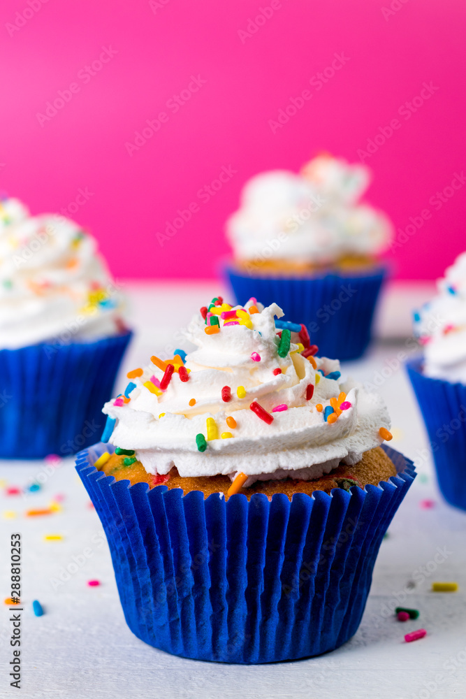 Cupcake saboroso de baunilha com chantily e brigadeiro granulado colorido sobre chuva de esferas azuis mais vela chuva de prata