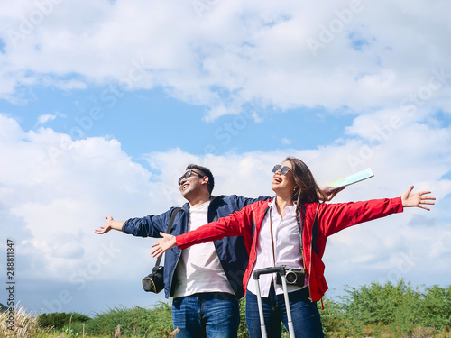 Asian tourists couple raising hands with nature background, lifestyle concept.