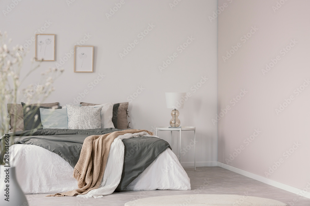 White and beige blankets on grey duvet on comfortable bed in bright bedroom interior - obrazy, fototapety, plakaty 