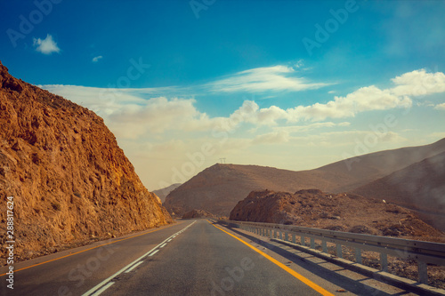 Driving a car on the mountain road in Israel. Desert landscape. Empty road. View from the car of mountain landscape with the striped sky. Israel