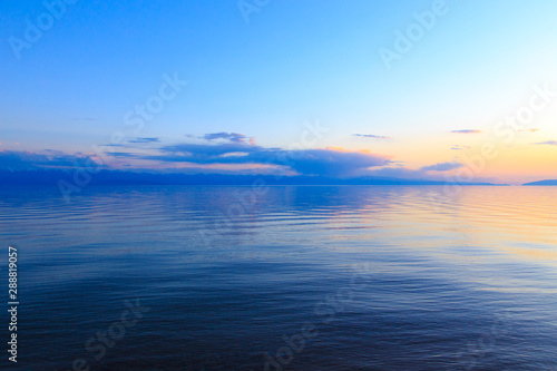 Beautiful sunset on a lake in the mountains. Kyrgyzstan  Issyk-Kul Lake. Bright sky  background in warm colors.