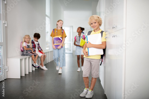 Boy wearing shorts and t-shirt standing in school corridor