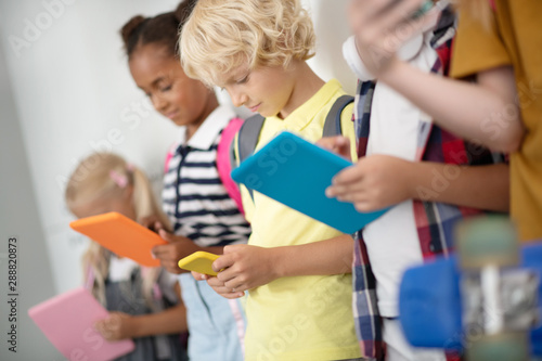 Children addicted to gadgets playing games in school corridor