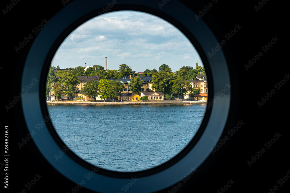 City summer landscape view of Stockholm seen from inside a ship cabin with round peep-hole window.