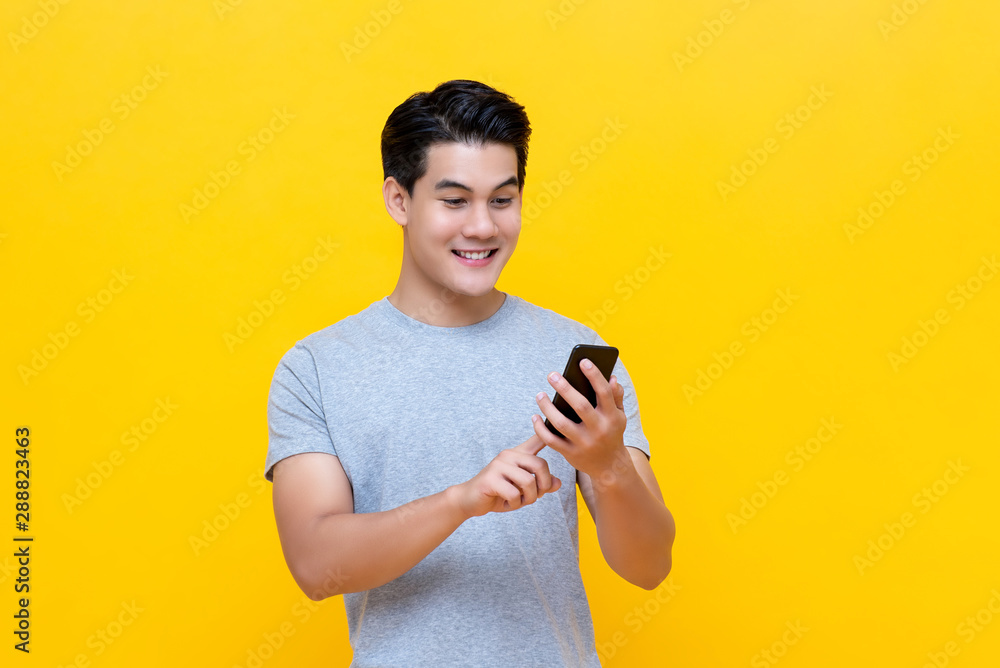 Smiling young good looking Asian man using smartphone Smiling young good looking Asian man using smartphone