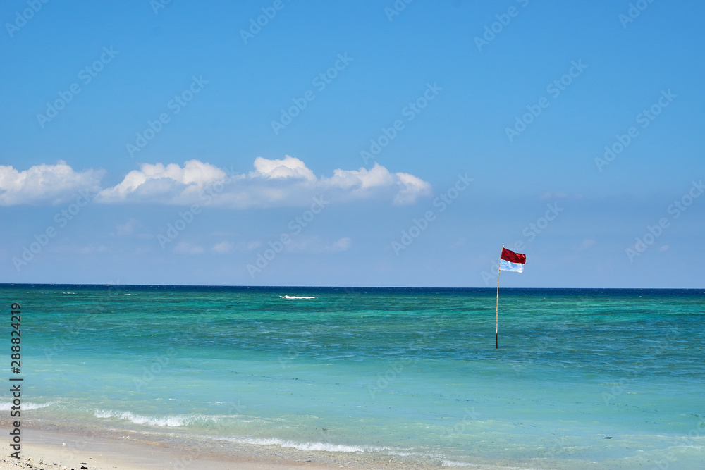 TRAWANGAN, INDONESIA - AUGUST.15.2019: Indonesian Flag in the Ocean at the Beach Gili Trawangan TRAWANGAN, INDONESIA - AUGUST.15.2019: Indonesian Flag in the Ocean at the Beach Gili Trawangan