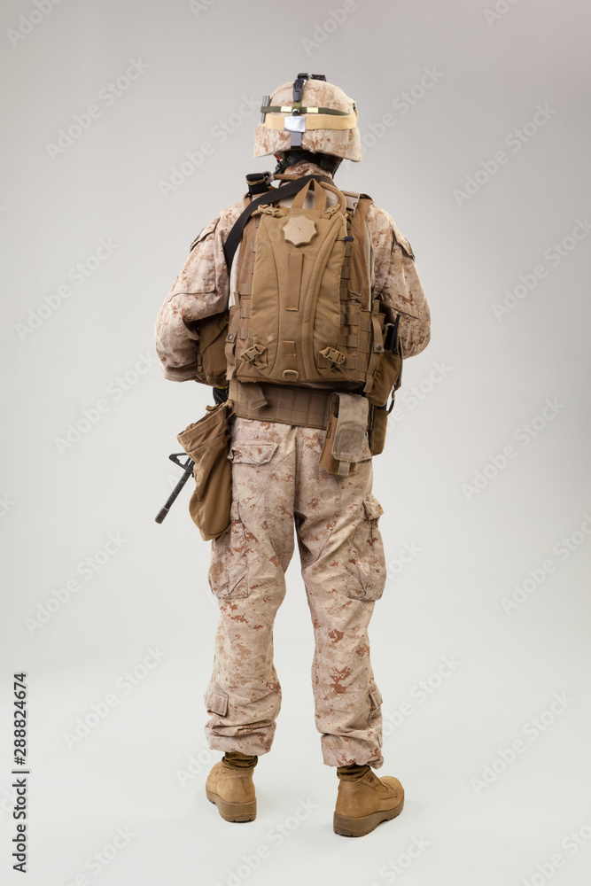 Soldier in US marines uniform with rifle on light grey background, studio shot Soldier in US marines uniform with rifle on light grey background, studio shot