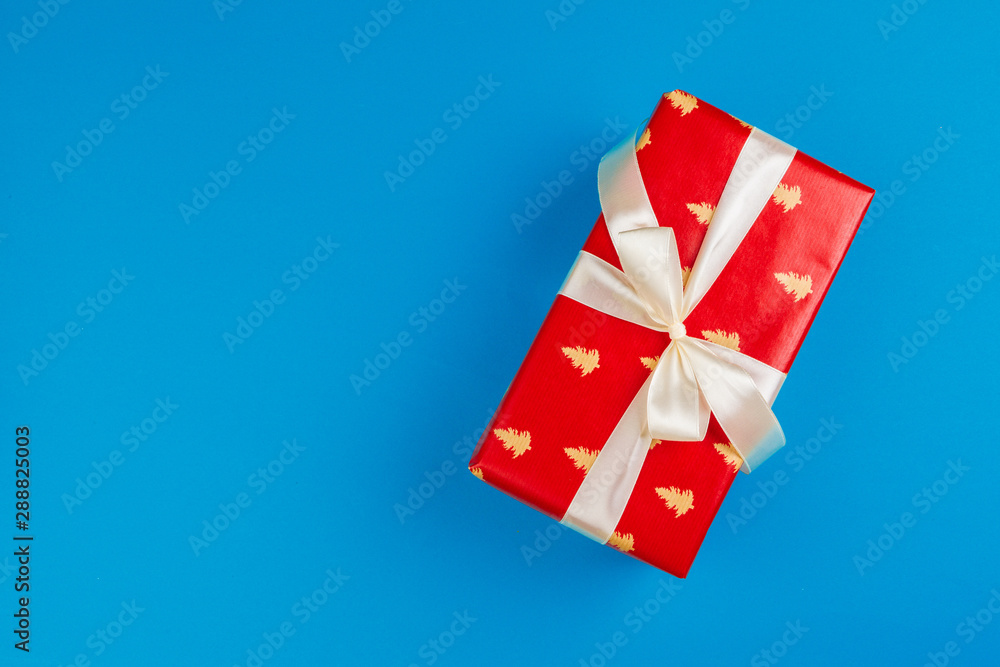 Flat lay of gift box decorated with bow on blue background Flat lay of gift box decorated with bow on blue background