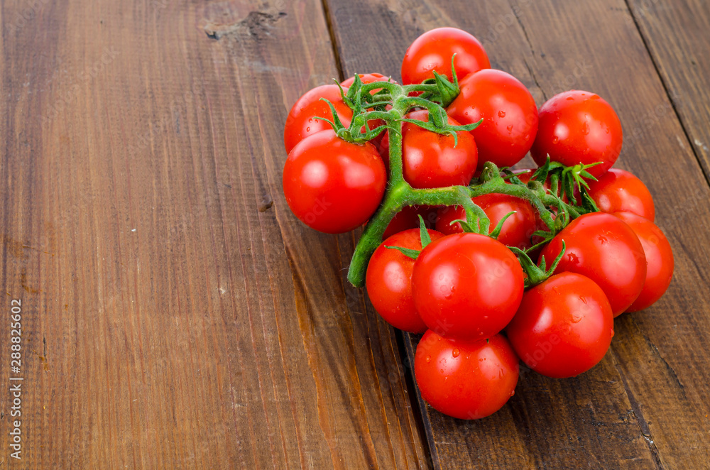 Bunch of red small round tomatoes on wooden background. Bunch of red small round tomatoes on wooden background.