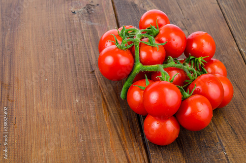 Bunch of red small round tomatoes on wooden background.