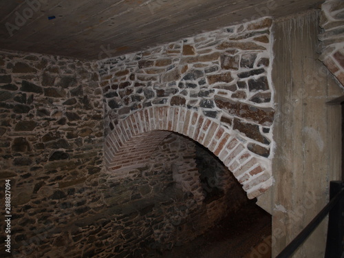 a semicircular arch of brick and stone in an ancient dungeon with a wooden ceiling