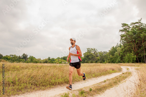 Man running outdoors with a beard in a sports uniform in nature, day, open air