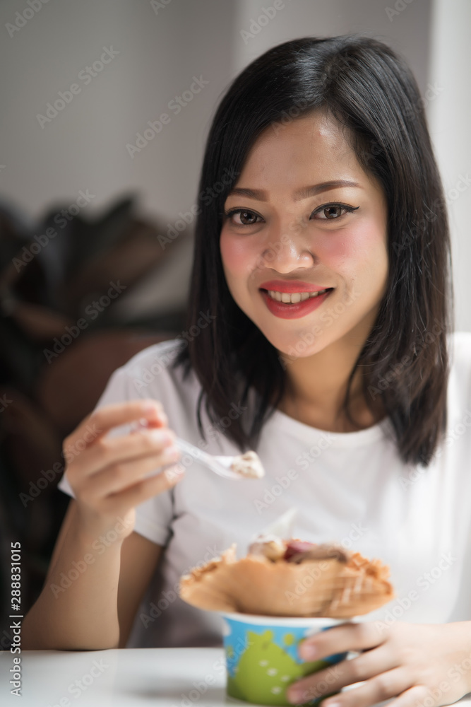 Asian young beautiful girl eating a dessert and smile at camera Asian young beautiful girl eating a dessert and smile at camera