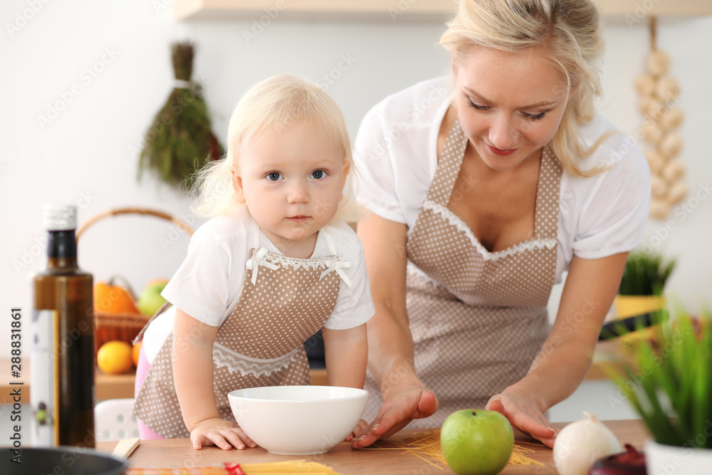 Happy mother and little daughter cooking in kitchen. Spending time all together, family fun concept Happy mother and little daughter cooking in kitchen. Spending time all together, family fun concept