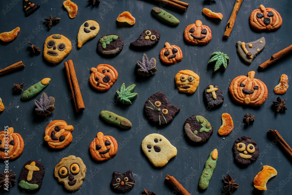 Pumpkin shape cookies, Halloween cookies jack o lantern, skeleton, ghost, witch and cinnamon sticks spices decoration in dark background low light with copy space Pumpkin shape cookies, Halloween cookies jack o lantern, skeleton, ghost, witch and cinnamon sticks spices decoration in dark background low light with copy space