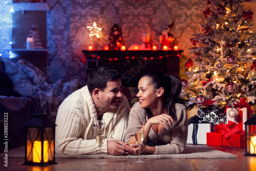 Photo of beautiful young couple at home in winter celebrating christmas