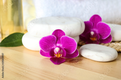 Spa stones and orchid flowers on wooden table