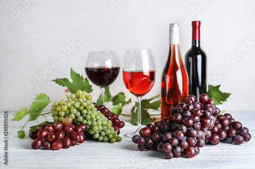 Fresh ripe juicy grapes and wine on white wooden table