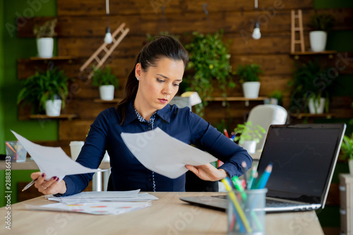 Brunette girl works in modern office with a laptop in front of her