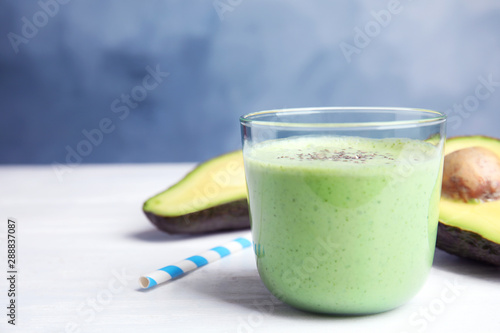 Glass of tasty avocado smoothie with chia seeds on white wooden table. Space for text