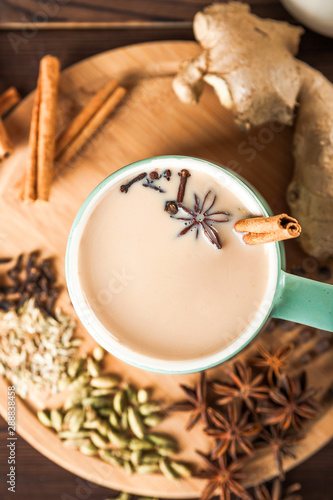 Details of still life in the home interior living room. Beautiful Cup of tea with milk, star anise, cinnamon on a wooden background. Cozy autumn-winter concept. Masala is a traditional hot spicy drink