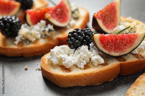 Bruschettas with cheese, figs and blackberries on grey table, closeup