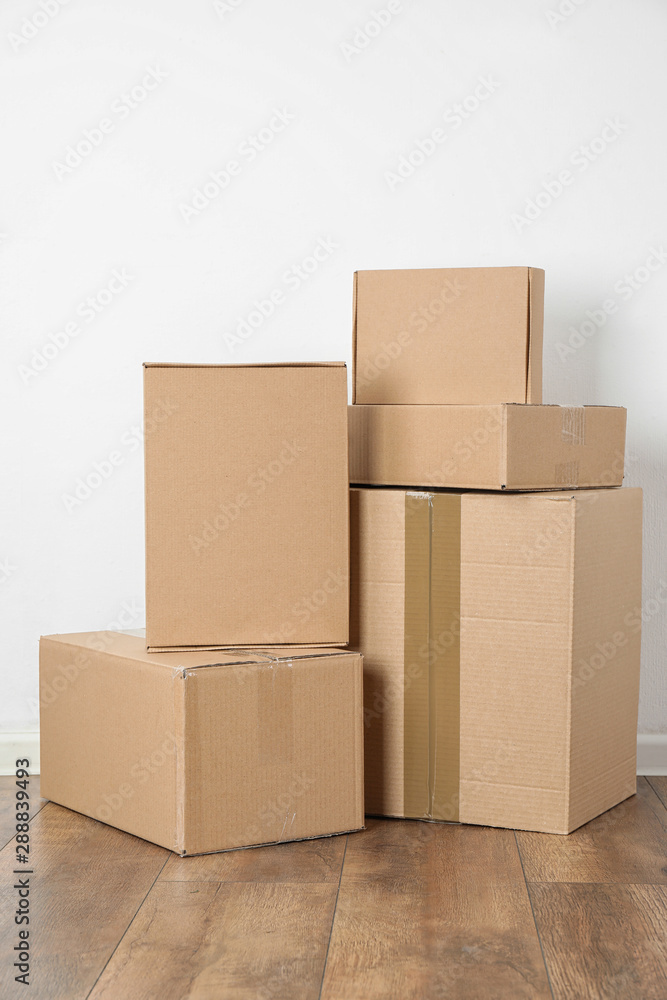 Pile of cardboard boxes near white wall indoors - obrazy, fototapety, plakaty 