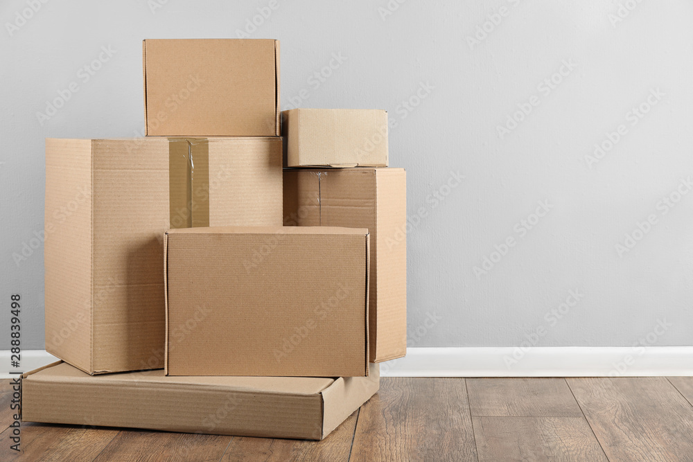Pile of cardboard boxes near light blue wall indoors. Space for text Pile of cardboard boxes near light blue wall indoors. Space for text